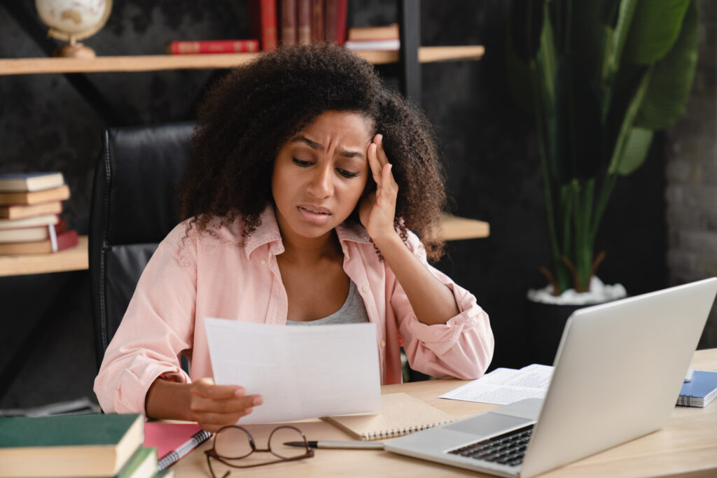 Migraine headache. Sad exhausted depressed tired woman reading document with debt loan mortgage